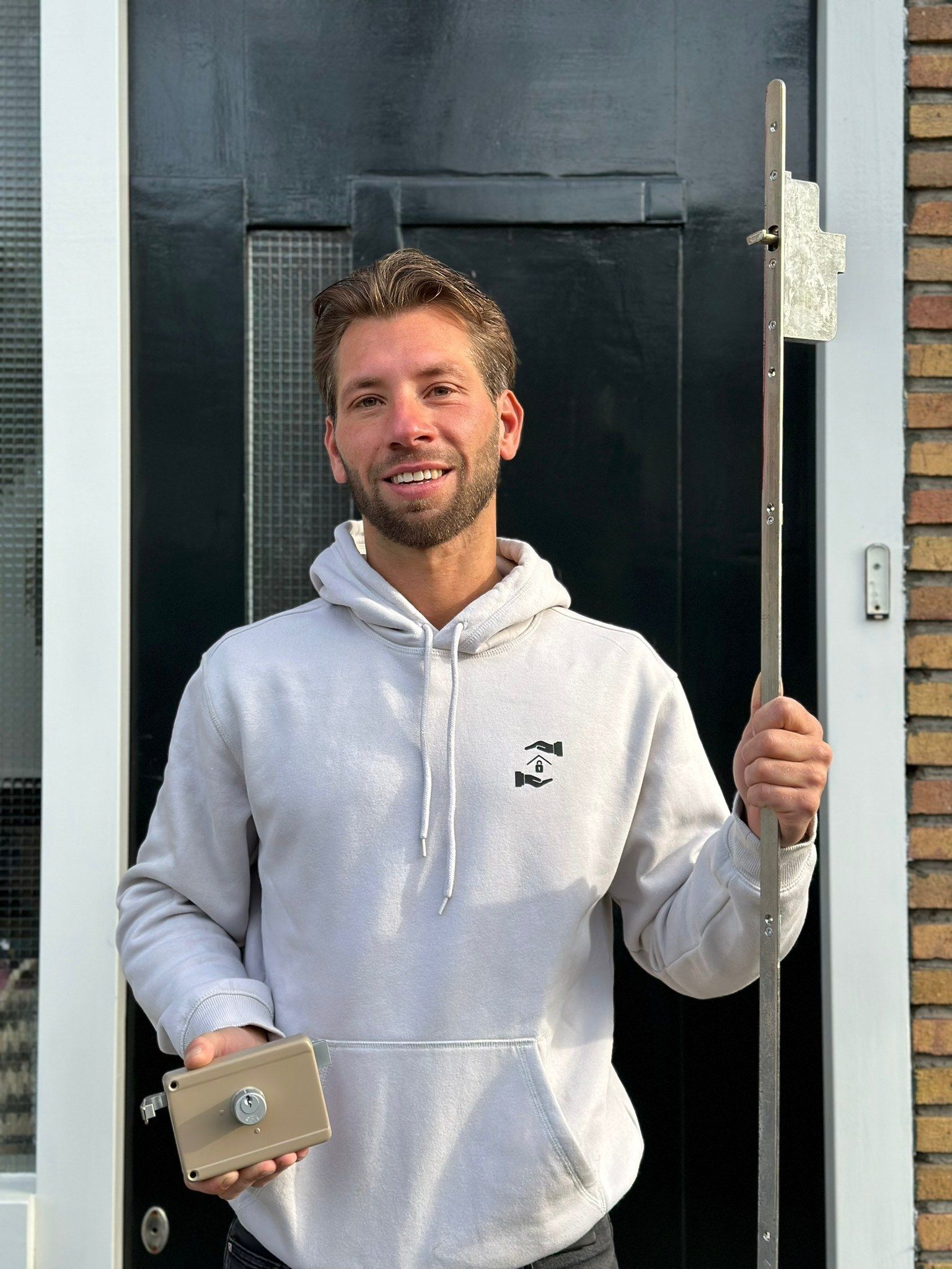 Beau, eigenaar van Mr. Slotenmaker, bij een voordeur met een opbouwslot en een meerpuntsluiting in zijn handen